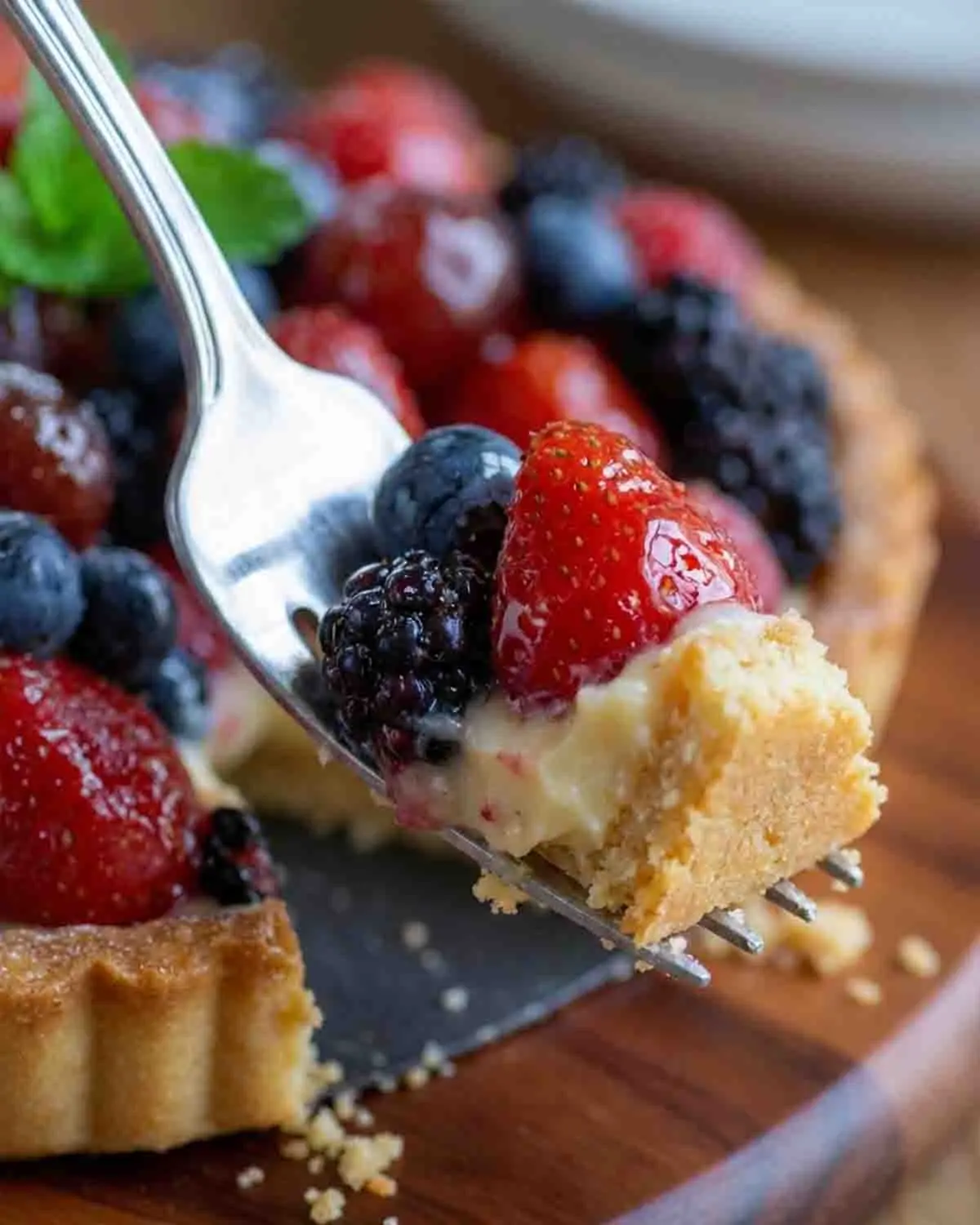 Bursting with Flavor: Berry Tart Pie - A Sweet Delight! 4 Close-up of a berry tart pie with fresh strawberries, blueberries, and blackberries on a flaky golden crust in a bright kitchen setting.