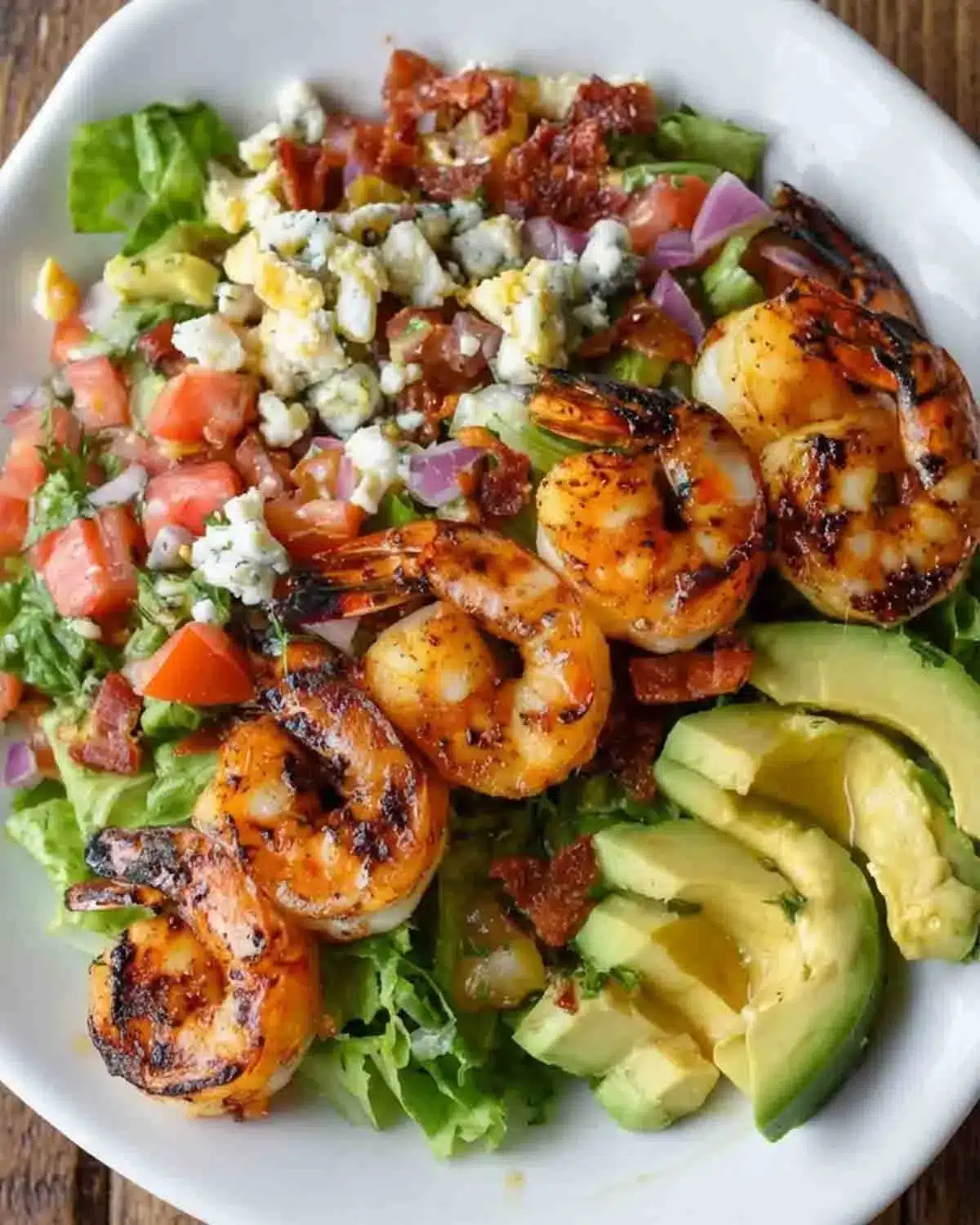 Grilled Shrimp Avocado Salad: A Burst of Zesty Freshness 4 Grilled shrimp avocado salad with charred shrimp, fresh lettuce, diced tomatoes, red onion, avocado slices, and crumbled cheese