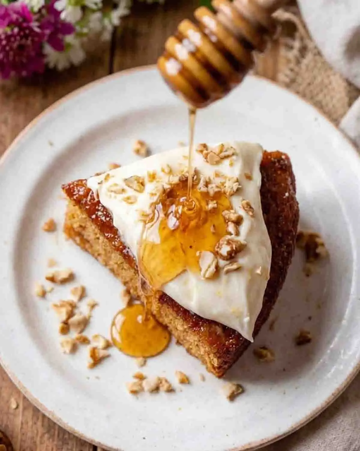 Sweet Sensation: Baking the Perfect Honey Cake 3 Honey cake slice with cream topping and honey drizzle served on white plate with nuts