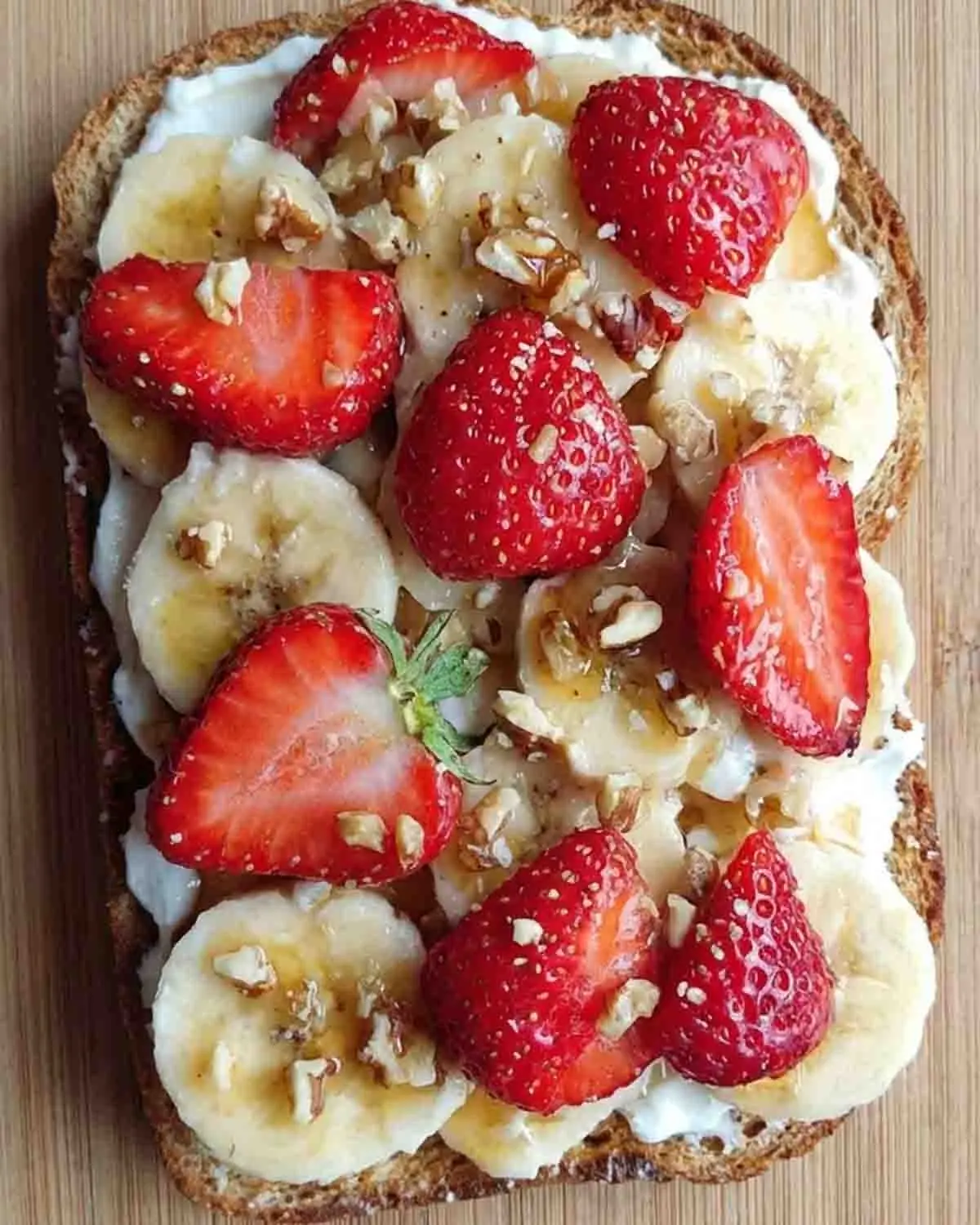 Strawberry Banana Toast: A Burst of Sweetness to Brighten Your Day 4 Close-up of strawberry banana toast topped with sliced bananas, fresh strawberries, creamy spread, chopped nuts, and a drizzle of honey on toasted bread.