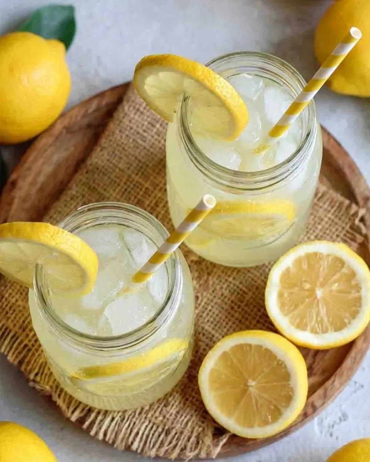 The Best Lemonade Recipe: A Refreshing Twist to Beat the Summer Heat 3 Fresh homemade lemonade in mason jars with ice and lemon slices on a rustic wooden tray