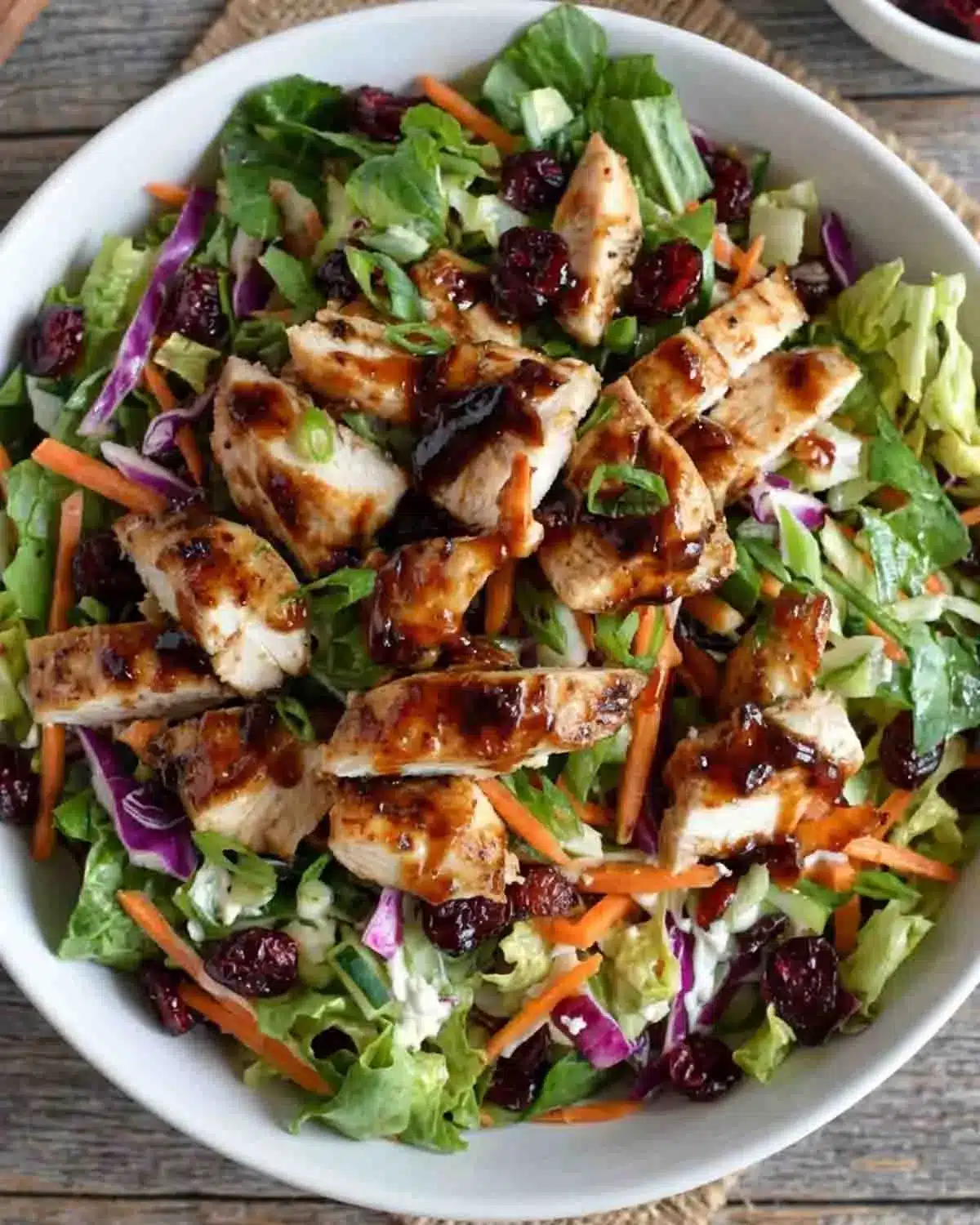 Asian Chicken Cranberry Salad 4 Asian chicken cranberry salad with grilled chicken pieces, dried cranberries, shredded cabbage, carrots, and sesame glaze dressing
