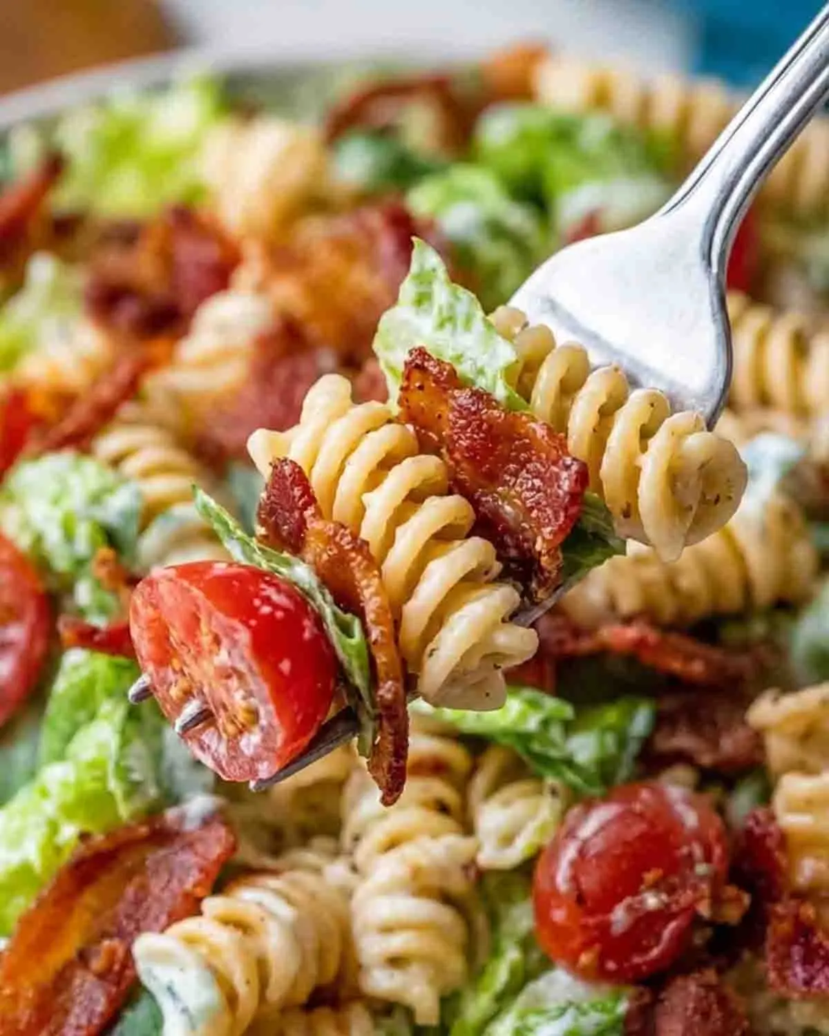 BLT Pasta Salad Recipe 4 close-up of creamy BLT pasta salad on a fork with crispy bacon, rotini pasta, lettuce, and cherry tomato