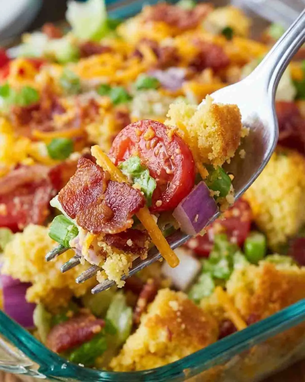 Cornbread Salad Recipe 4 Close-up of cornbread salad recipe with bacon, tomatoes, cheese, and vegetables on a fork