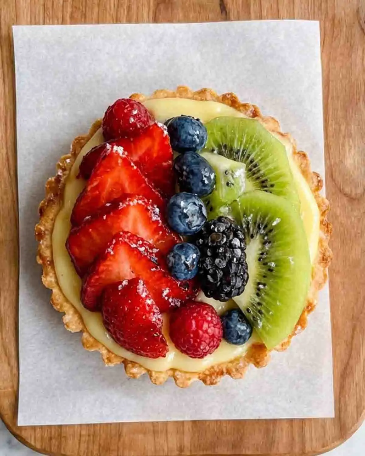 Fruit Tart with Pastry Cream 3 Close-up of fruit tart with pastry cream topped with strawberries, blueberries, blackberries, and kiwi on a golden tart crust