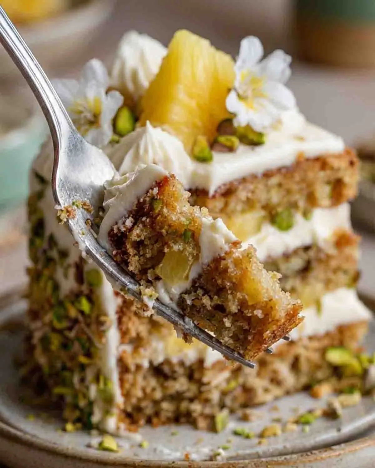 Pistachio Pineapple Cake 3 Close-up of pistachio pineapple cake slice on a fork showing moist layers, creamy frosting, pineapple chunks, and chopped pistachios