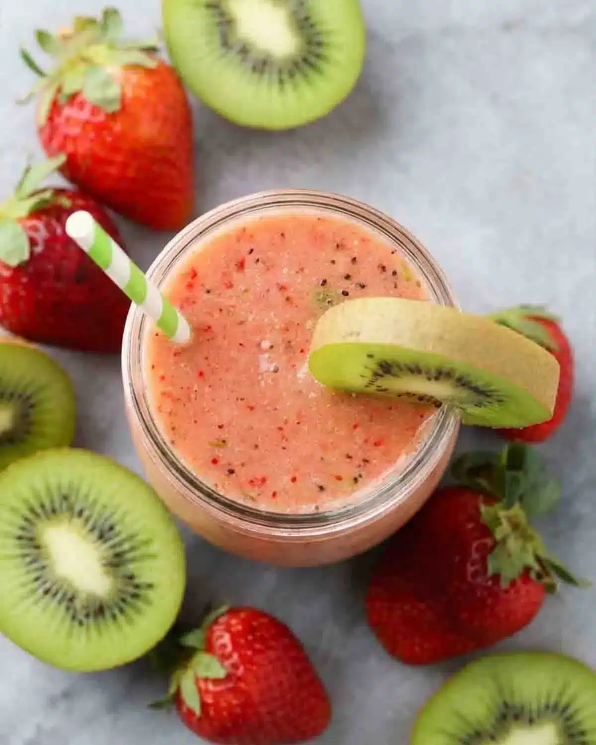 Strawberry-Kiwi Smoothie 3 Top view of Strawberry-Kiwi Smoothie in a glass jar with fresh kiwi slices and strawberries around