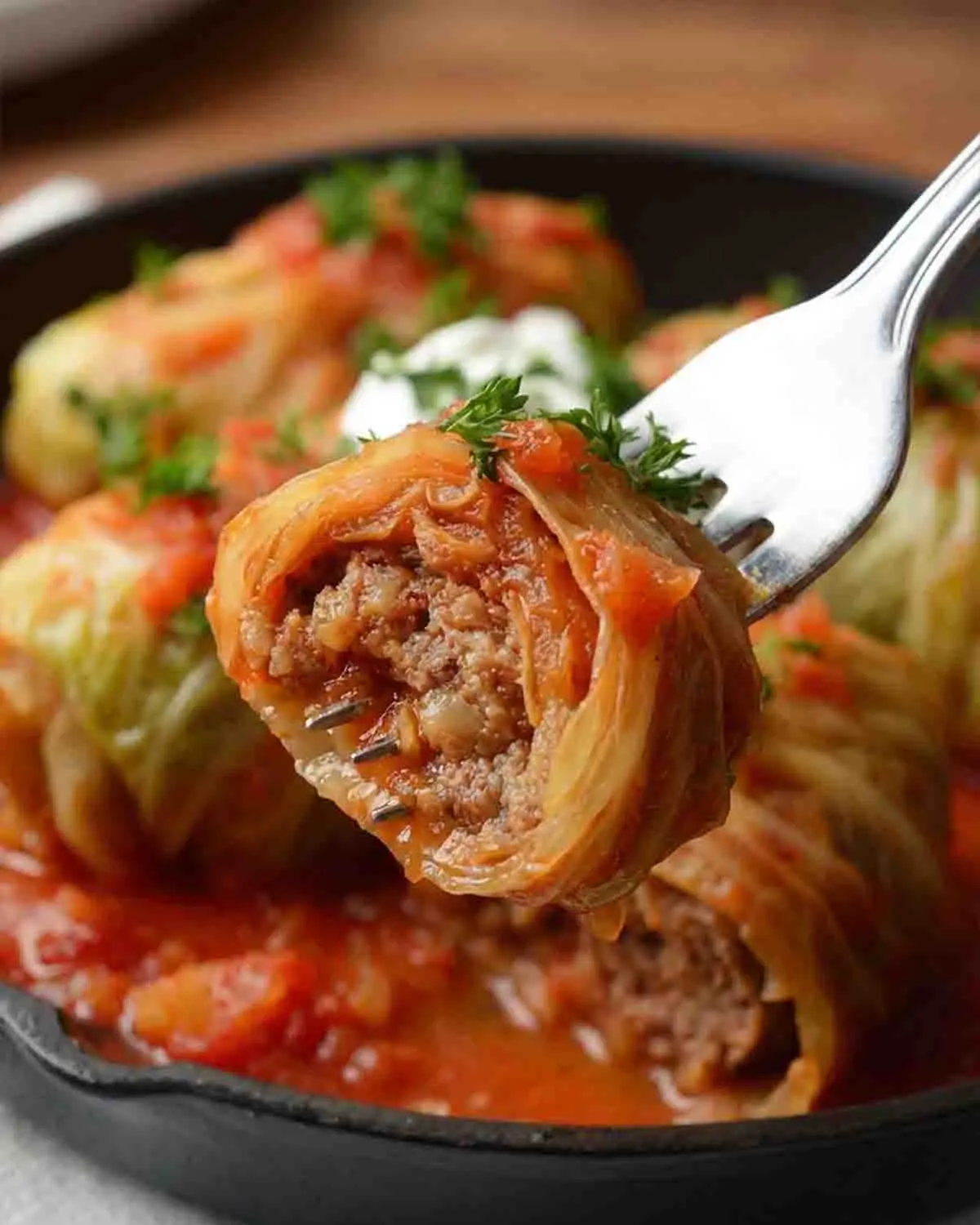 Stuffed Cabbage Rolls Recipe 4 Close-up of stuffed cabbage roll on a fork showing juicy ground meat and rice filling, coated in rich tomato sauce with parsley garnish