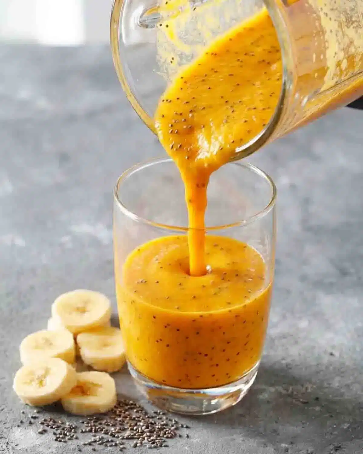 Tropical Chia Smoothie 3 Tropical chia smoothie with mango, banana, and pineapple poured into a glass, showing creamy texture with chia seeds