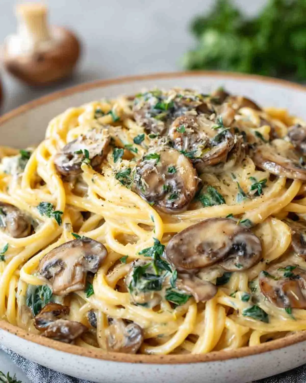 Creamy garlic mushroom pasta with fettuccine, sautéed mushrooms, and Parmesan cream sauce garnished with fresh herbs in a bowl