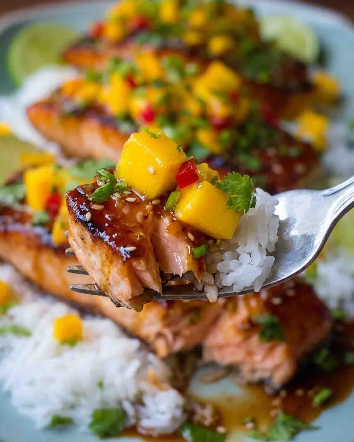 Mango Teriyaki Salmon Recipe 4 Close-up bite of mango teriyaki salmon with rice, topped with fresh mango salsa and sesame seeds